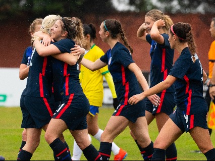 US women soccer players hugging each other after a goal.